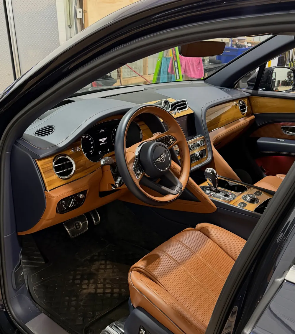 Bentley Bentayga interior with tan leather seats and wood dash, detailed by Stumptown Detailing