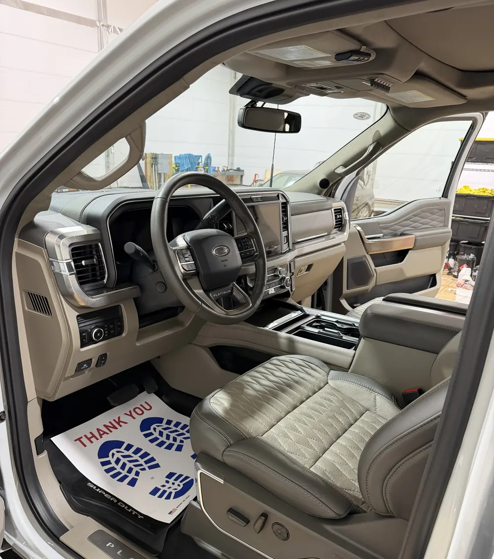 Ford Super Duty interior with gray leather seats and a paper thank-you floor mat after a detail at the Stumptown Detailing shop